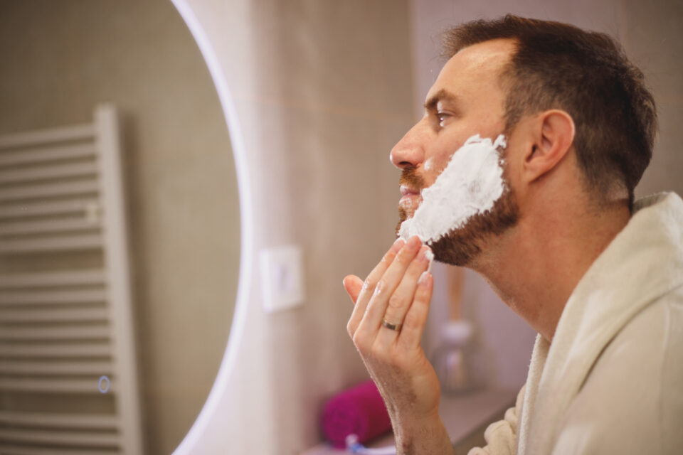 Bald man applying aftershave balm to his freshly shaved head in the mirror