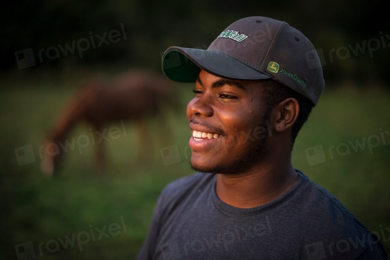 Bald man wearing a fitted baseball cap outdoors in sunlight