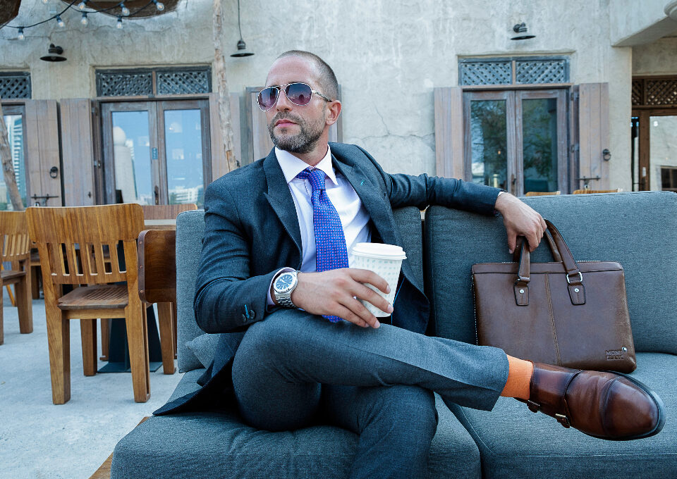 Bald man wearing rectangular sunglasses outdoors in sunlight